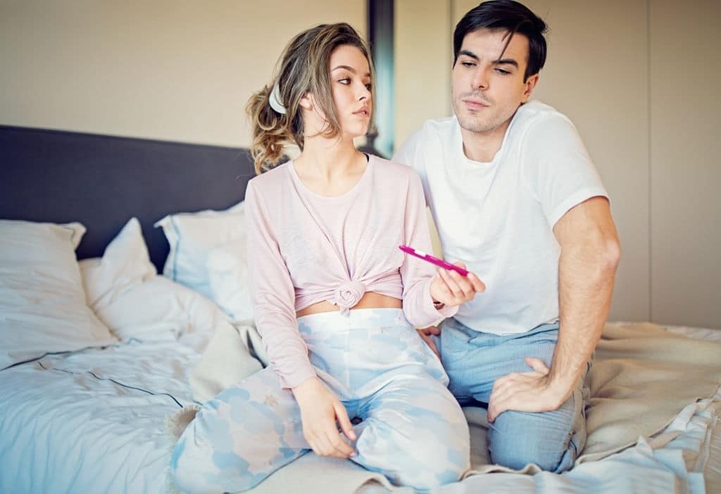 Shocked couple is looking positive pregnancy test in the bedroom infertilidad