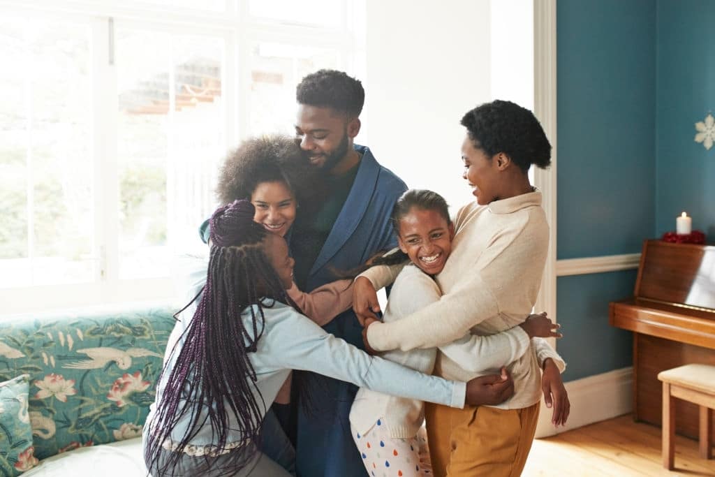 Cheerful girls embracing young man and woman at home during Christmas festival padres con VIH