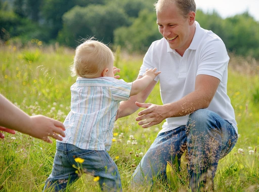 Baby boy learning to walk: making his first steps from one parent to the other. 20 consejos para papás primerizos